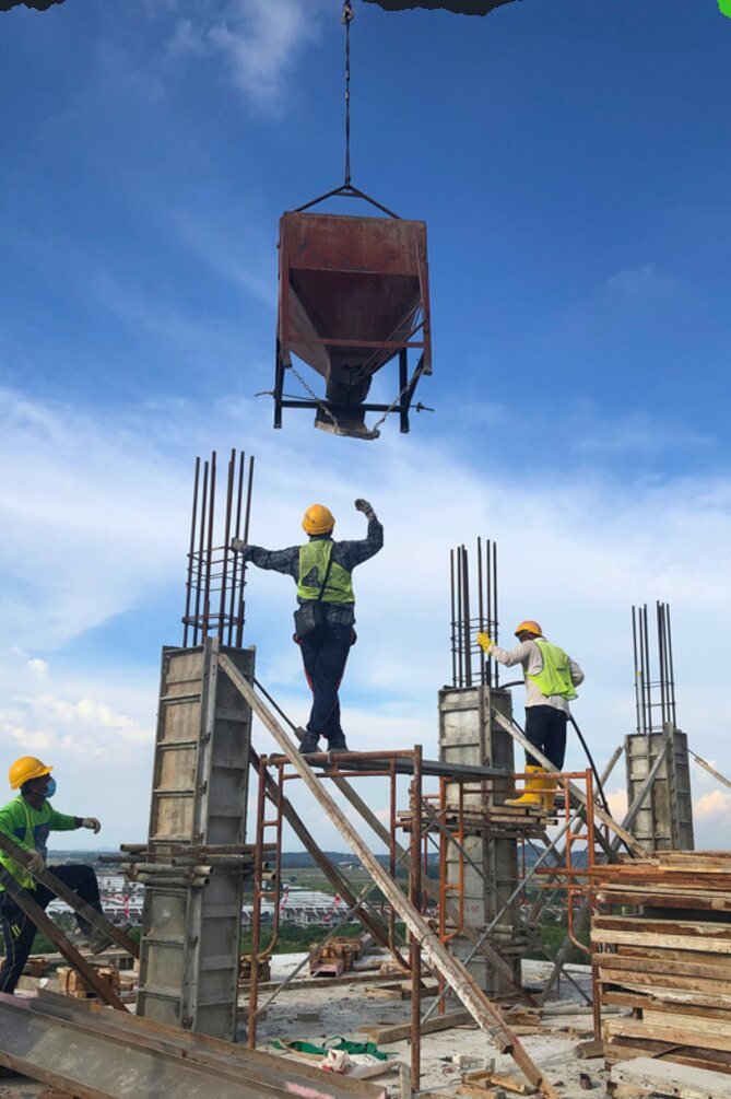 Construction workers pouring concrete for a structural frame