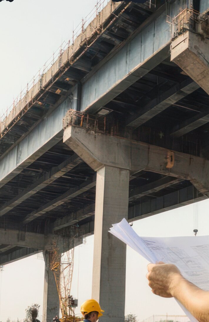 Engineer reviewing plans under a highway bridge