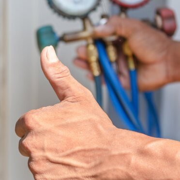 Technician checking refrigerant pressure gauges