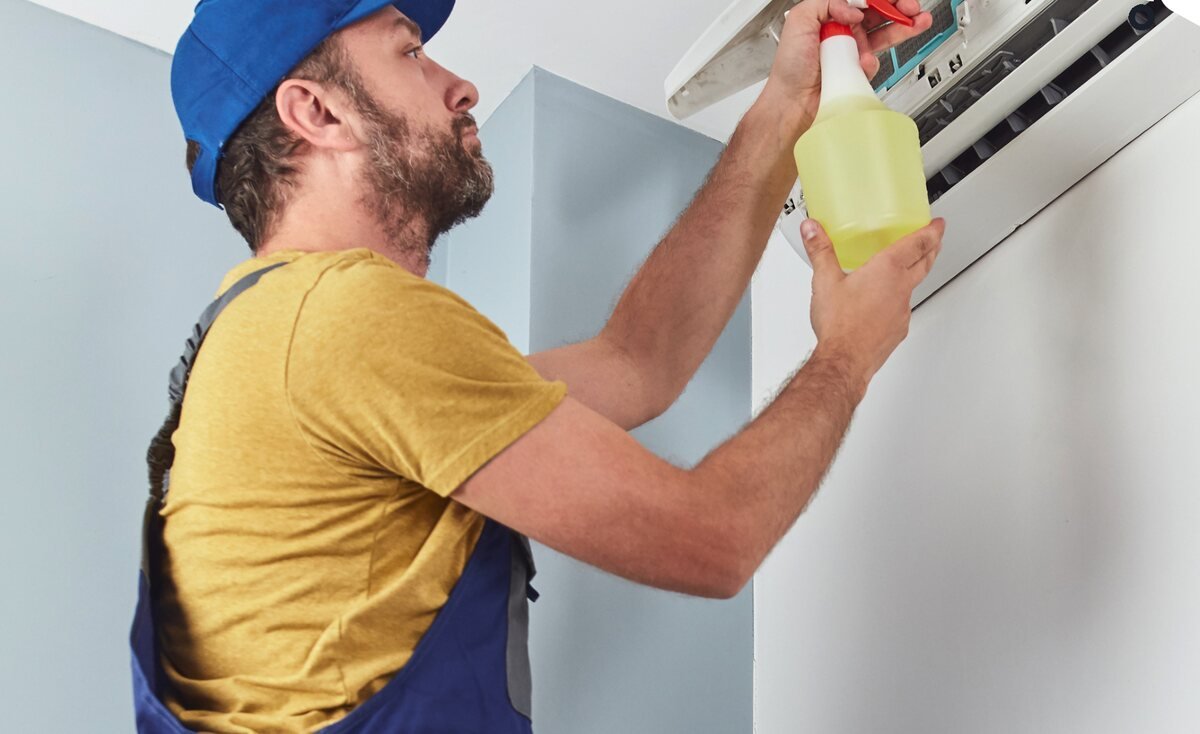 Technician cleaning and troubleshooting an air conditioner
