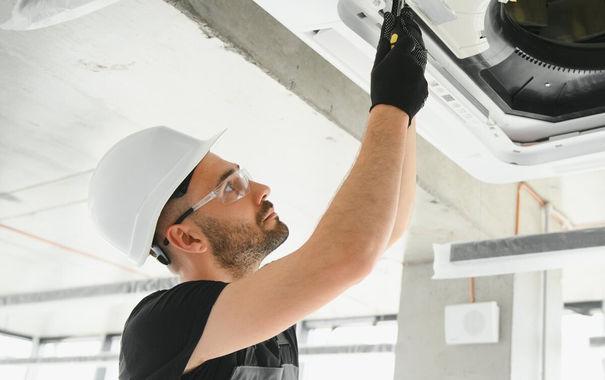 Technician installing a ceiling cassette air conditioning unit